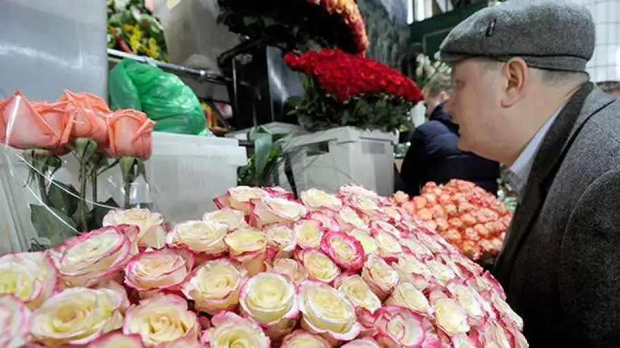 Мужчина средних лет покупает на рынке букет роз