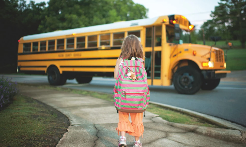 Девочка на фоне школьного автобуса