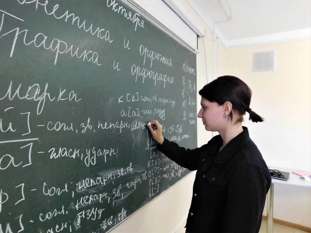 Ученица старших классов в школе на уроке русского языка у доски