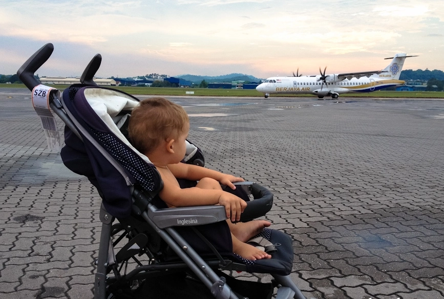Ребёнок в коляске смотрит на самолёт
