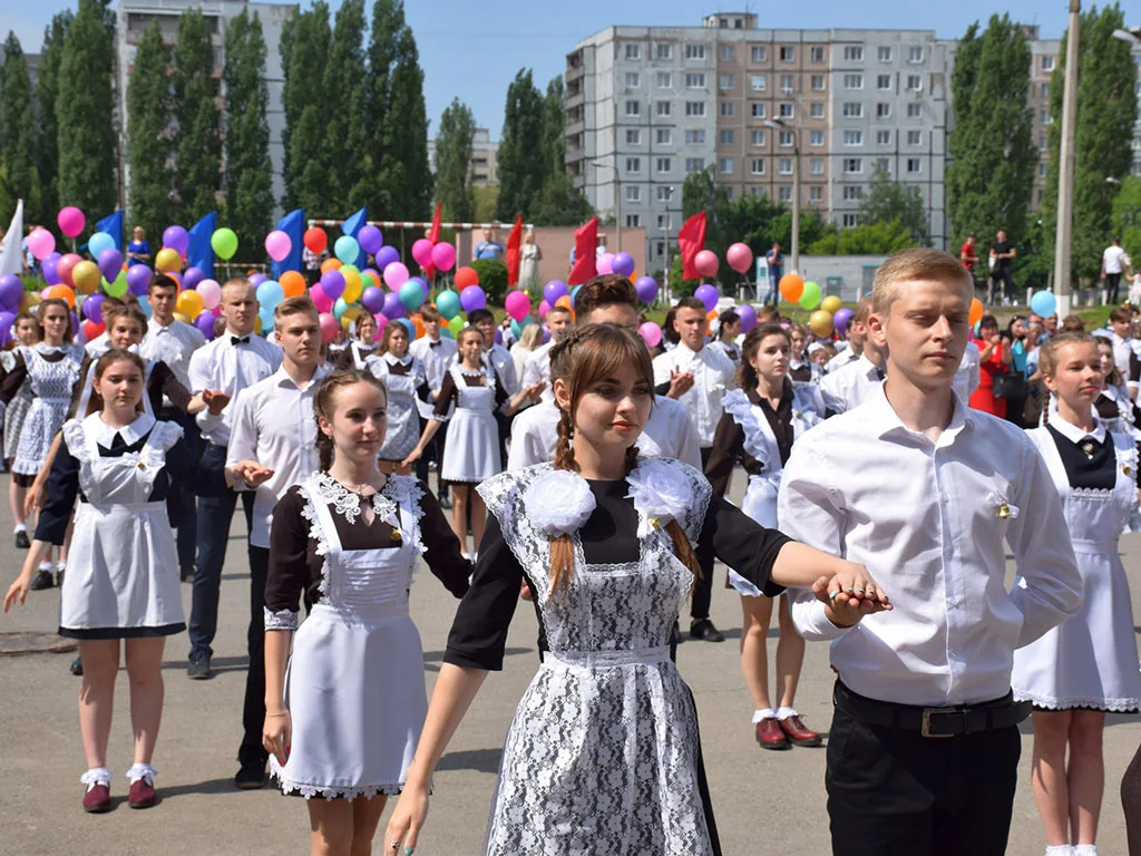 Линейка, последний звонок, учащиеся в парадной форме танцуют перед школой